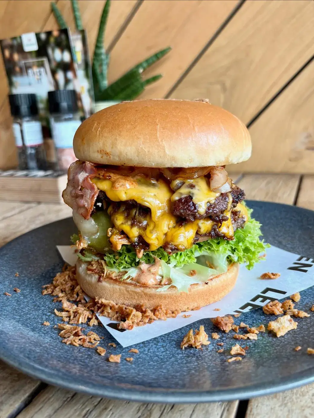 Dubbele cheeseburger met bacon en crispy uitjes op een bord bij Club LEEN