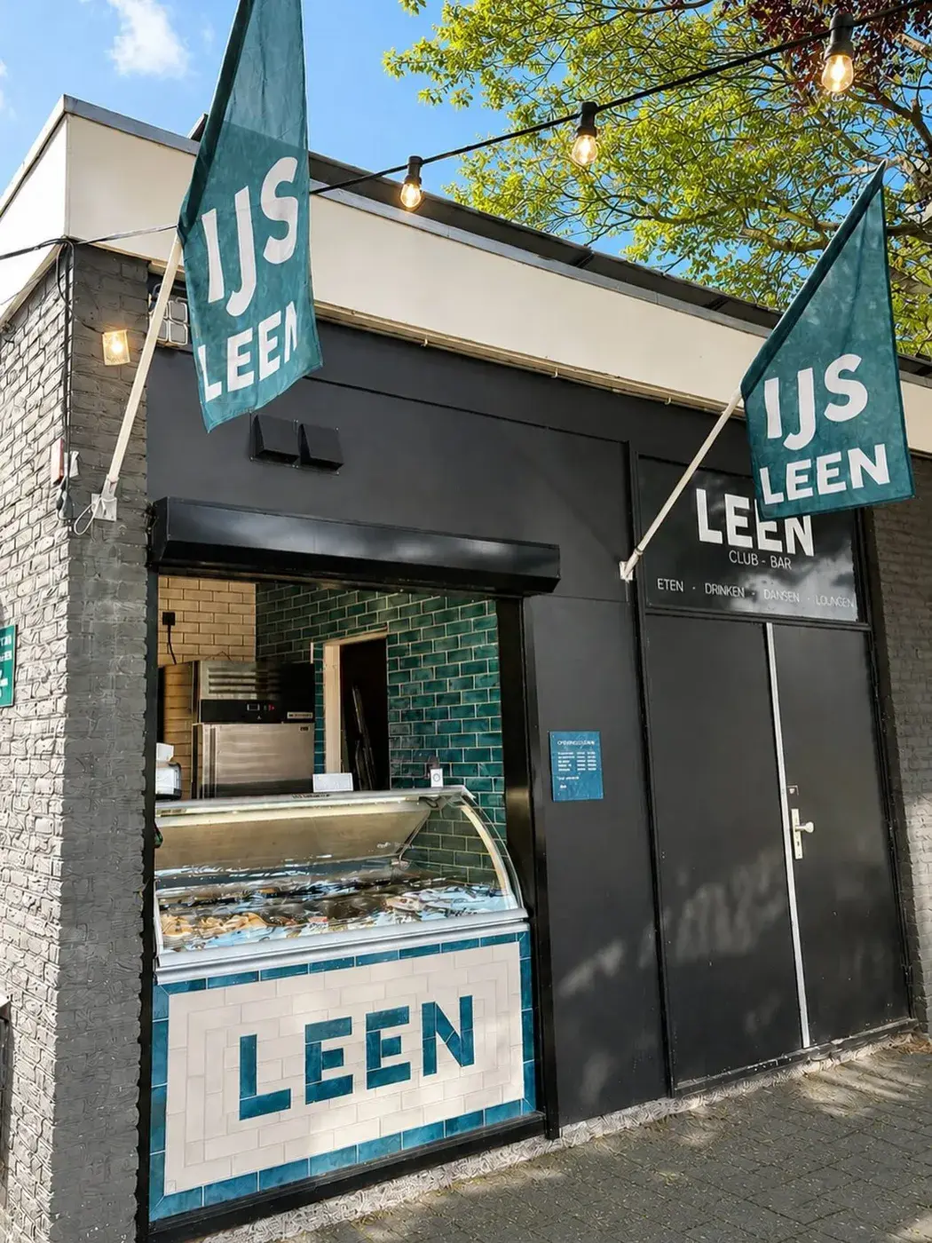 Buitenzijde van Club LEEN met het ijsloket en LEEN-vlaggen aan de Molenweg in Rozenburg