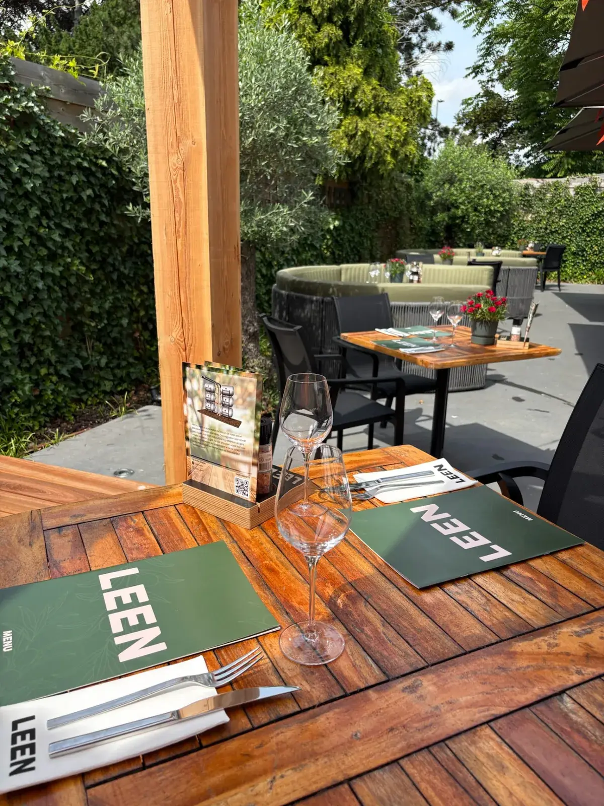 Groene LEEN-menukaarten en gedekte houten tafel op het terras van Club LEEN