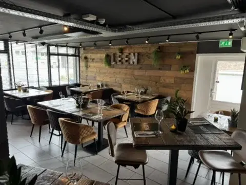 De Eetkamer van Club LEEN met houten accentwand, LEEN-logo en gedekte tafels