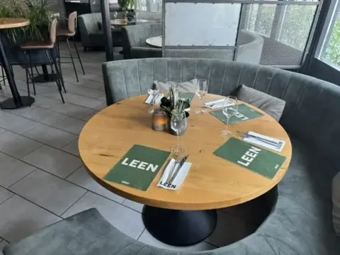 Ronde zitbank in De Lounge van Club LEEN met gedekte tafel en uitzicht naar buiten