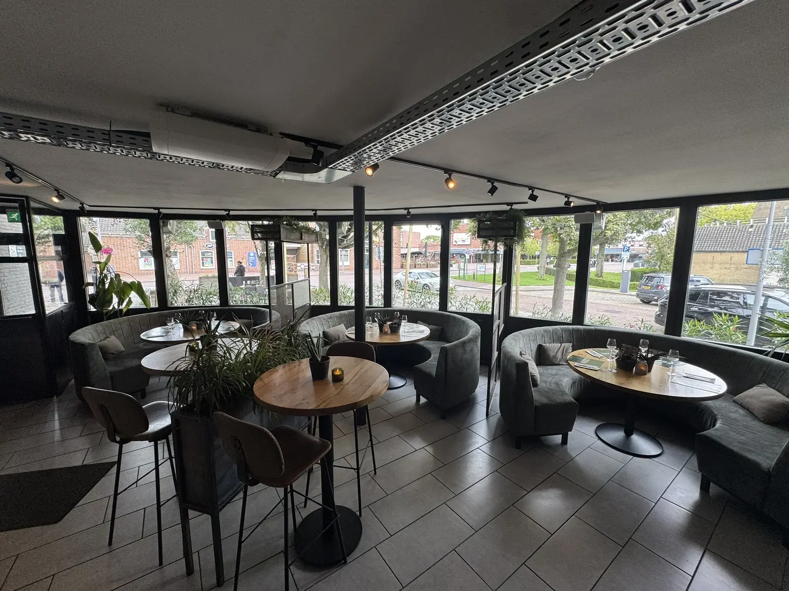 Panoramische lounge van Club LEEN met ronde banken, houten tafels en uitzicht op de Molenweg