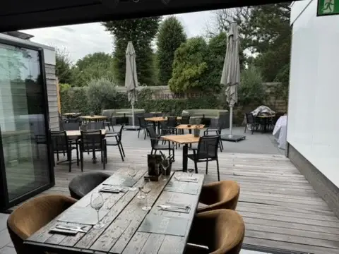 Houten terras in De Tuin van LEEN met gedekte tafels tussen het groen