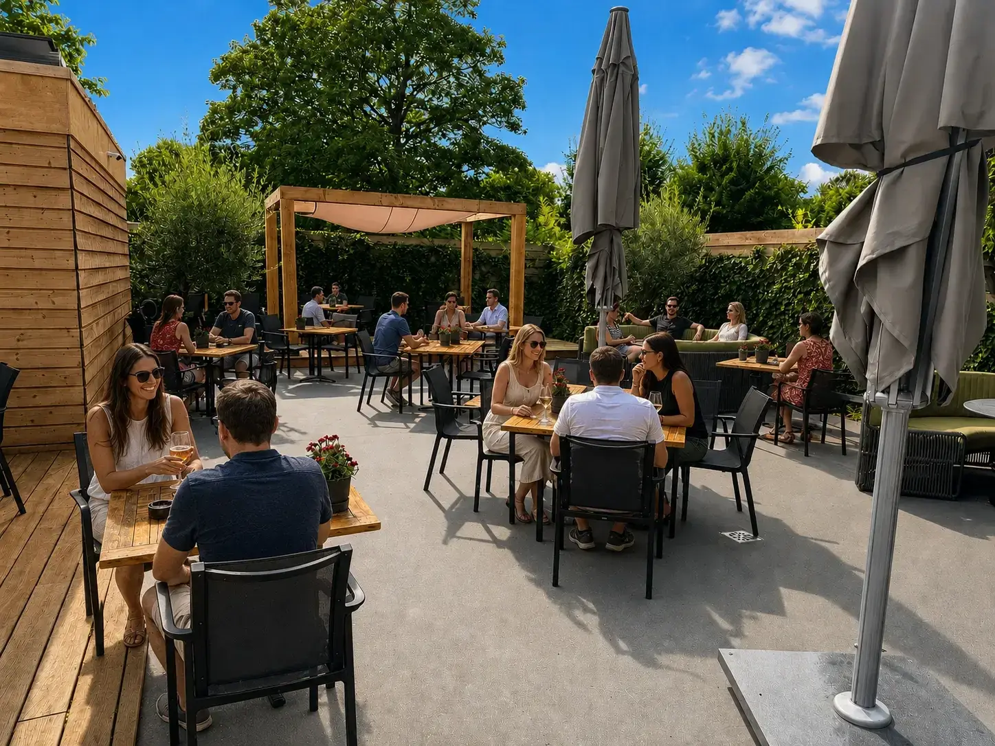 Zonnige Tuin van LEEN met gasten aan houten tafels, parasols, loungebanken en een pergola tussen het groen