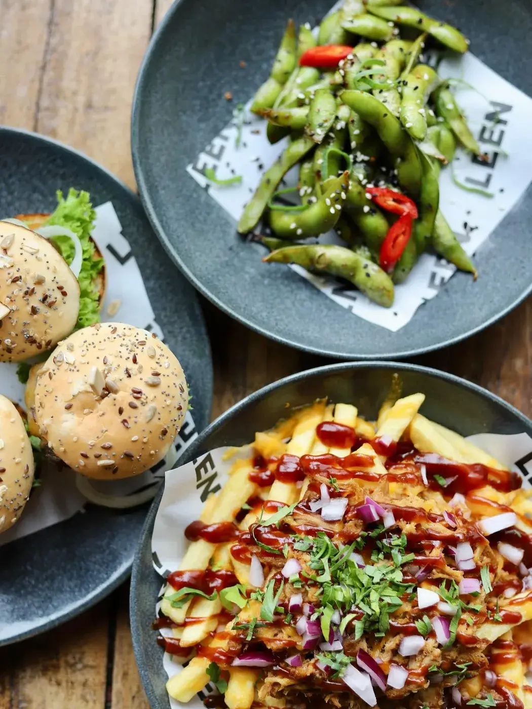 Deelgerechten met edamame, broodjes en loaded fries op tafel bij Club LEEN