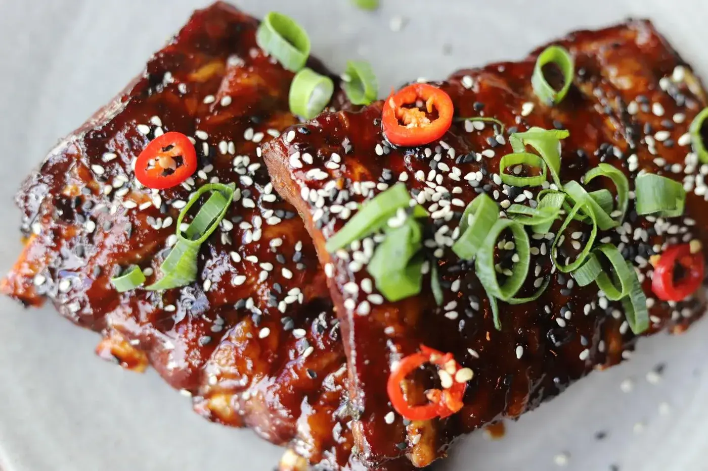 Glazed spareribs met sesam en rode peper op een bord bij Club LEEN